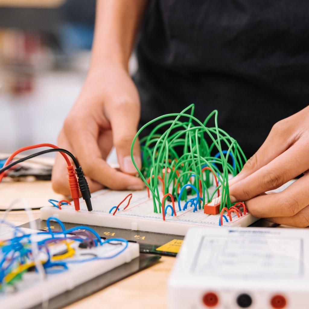 A picture of someone's hands working on a set of bread board circuits.